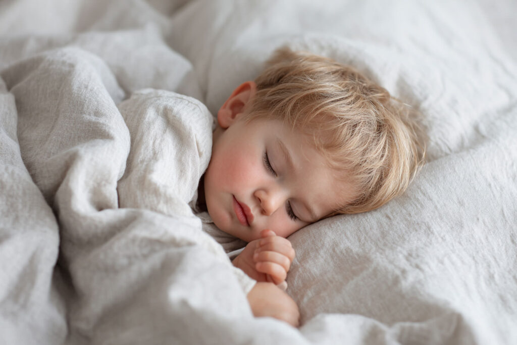 Kleinkind schläft friedlich im Bett. Gesunder Schlaf nach Schlafberatung